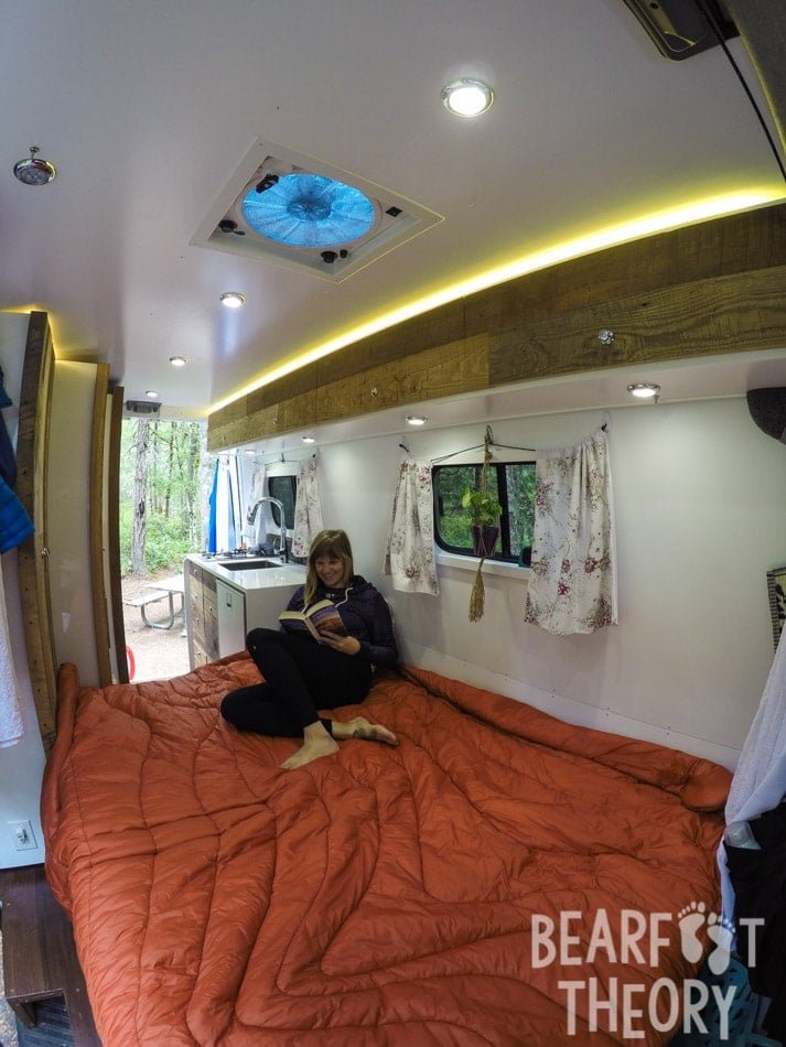 Interior photo of Alaina's first MErcedes Sprinter camper van showing the convertible sofa bed unfolded into a queen size bed