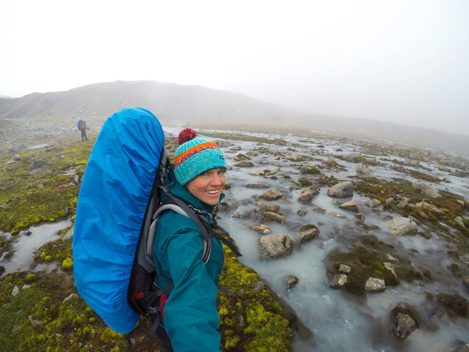 Alaina wearing backpacking backpack protected with rain cover in gray, misty landscape