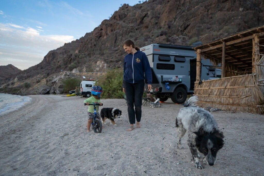 Alaina Hermiston and her son on a strider bike standing next to Rossmonster Baja Trail on a beach in Baja