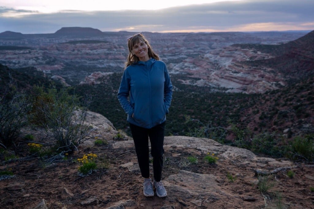 Alaina Hermiston standing on the edge of a desert canyon at sunset