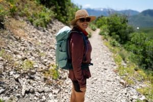 Alaina Hermiston wearing the Deuter Trail 28 SL backpack on a trail in Park City with green foliage