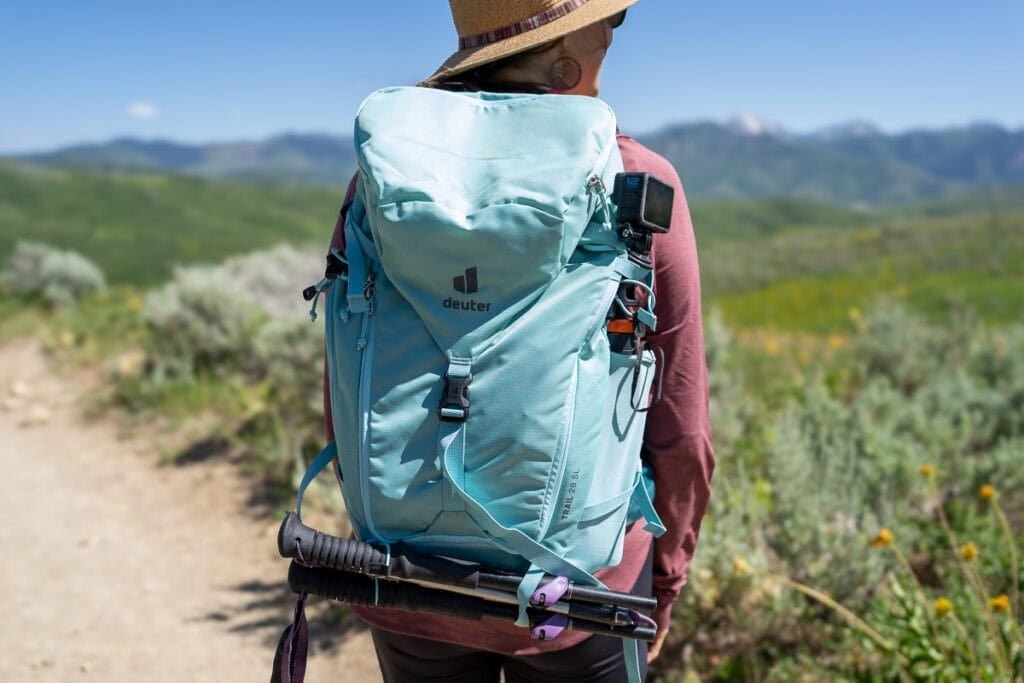 Alaina Hermiston wearing the Deuter Trail 28 SL backpack on a trail in Park City with green foliage
