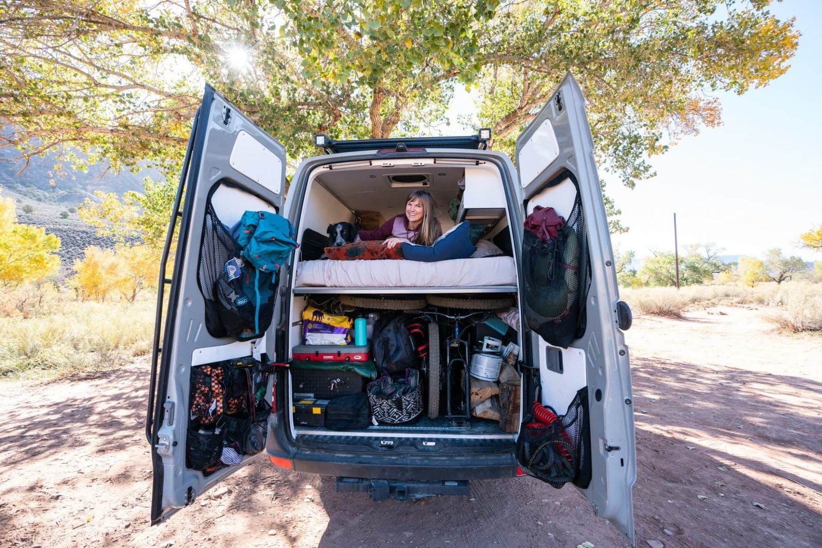 Terrain Spark founder Alaina Hermiston lying in the bed in her Sprinter Van with the back doors open