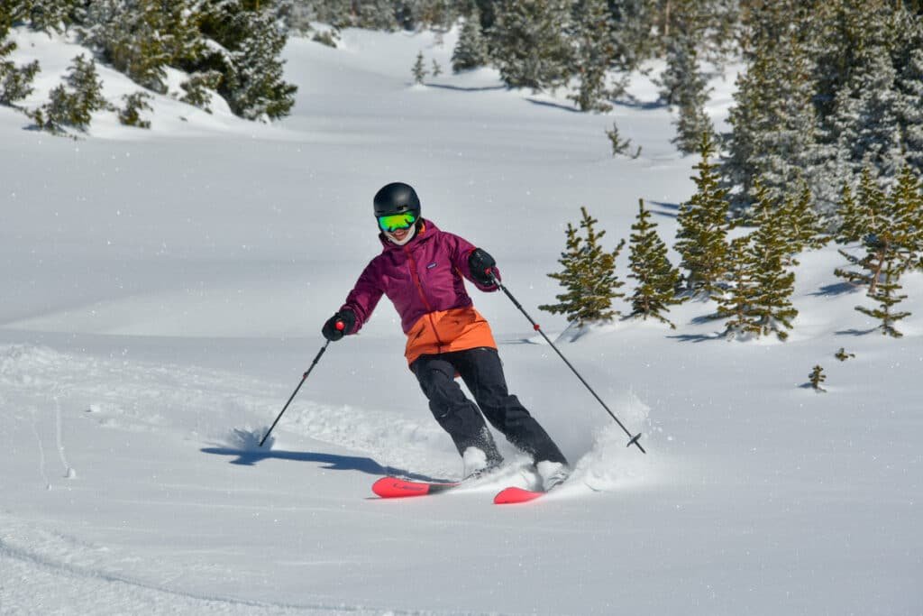 Terrain Spark founder Alaina Hermiston skiing powder wearing a pink Patagonia jacket at irwin lakes in Crested Butte Colorado