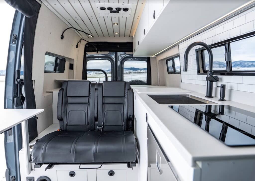 Sprinter Van converted by Rossmonster. Photo shows a bench seat next to a galley