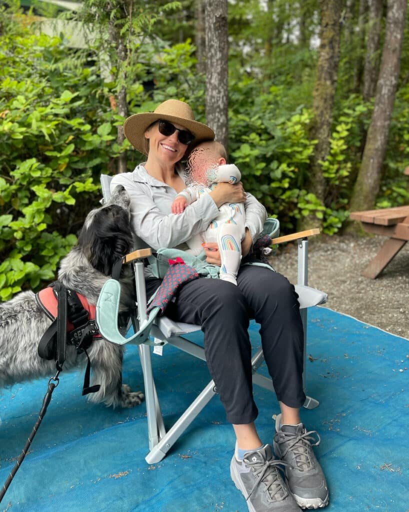 Terrain Spark founder Alaina Hermiston sitting in a Dometic Go camping chair holding her baby at a campsite
