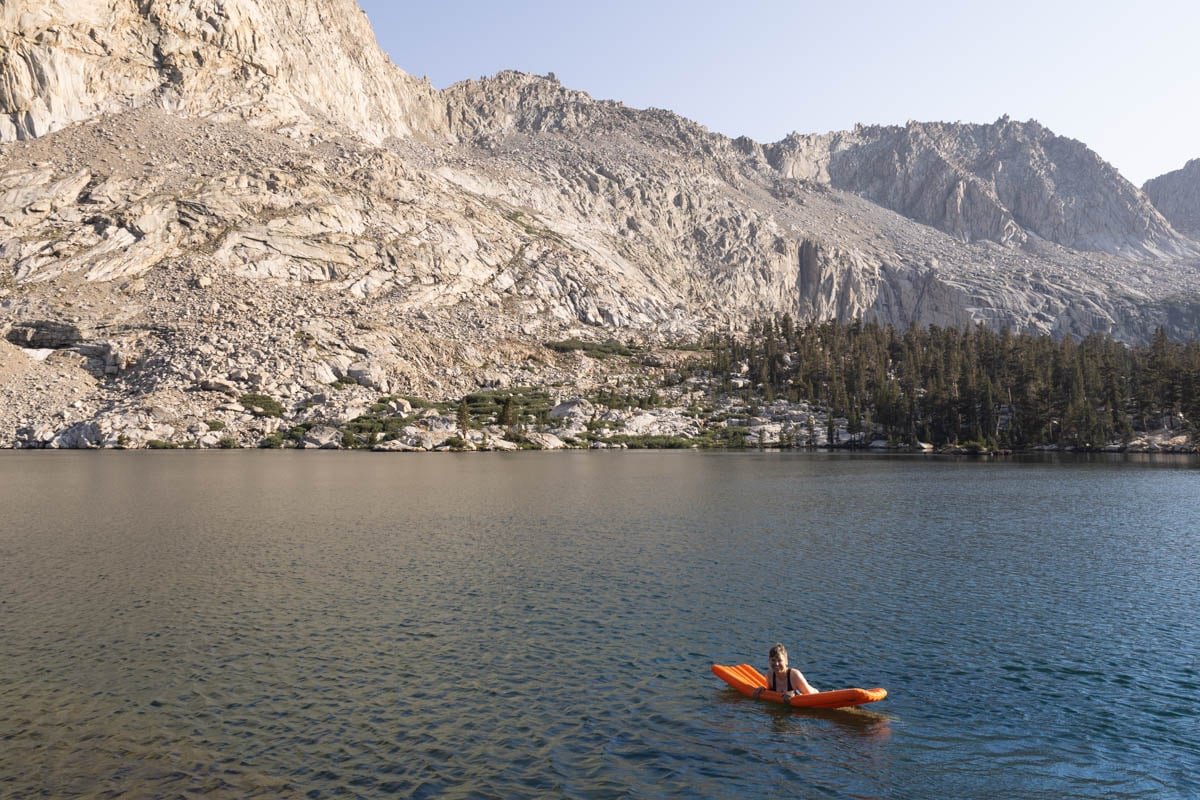 Alaina Hermiston swimming in a lake in Sequoia National Park using a sleeping pad as a float