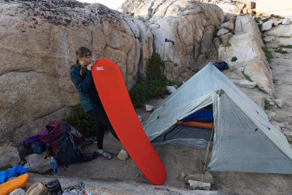 Alaina Hermiston blowing up a Thermarest Sleeping Pad next to her ZPacks Triplex tent in Sequoia National Park