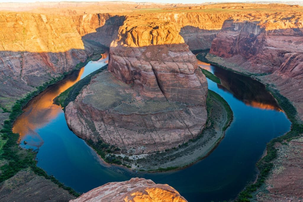 Sun casting glow on rocks above Horseshoe Bend in Arizona