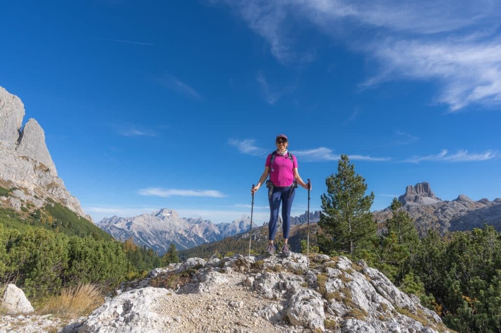 Alaina Hermiston hiking in Italy near Cortina-d-Ampezzo wearing blue lululemon Wundertrain leggings and a pink shirt wirth mountains in the background