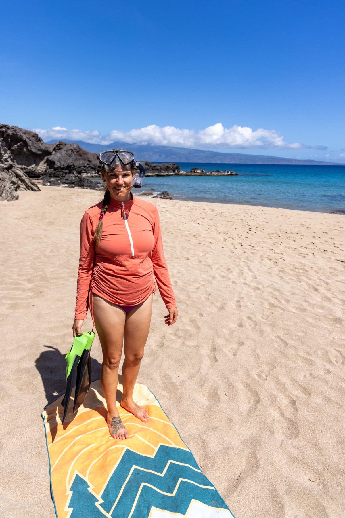 Alaina Hermiston standing on a towel on the beach in Maui with a snorkel on her head