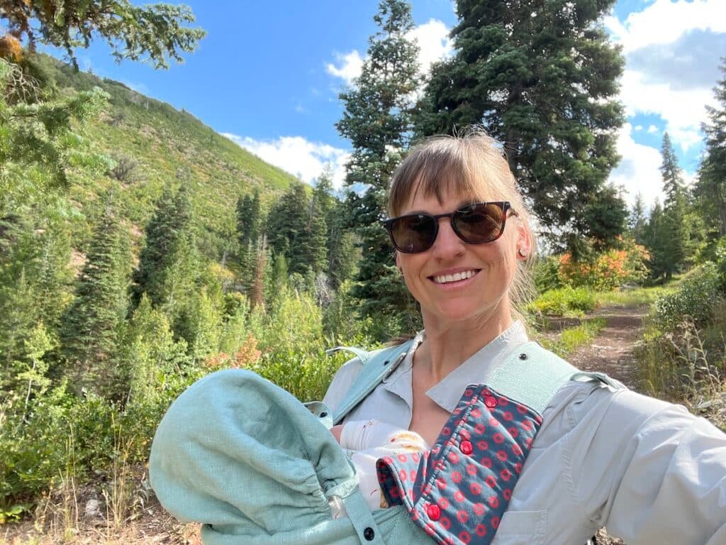 Alaina Hermiston hiking with baby in baby carrier in park city utah wearing the Roka Rory 2.0 sunglasses