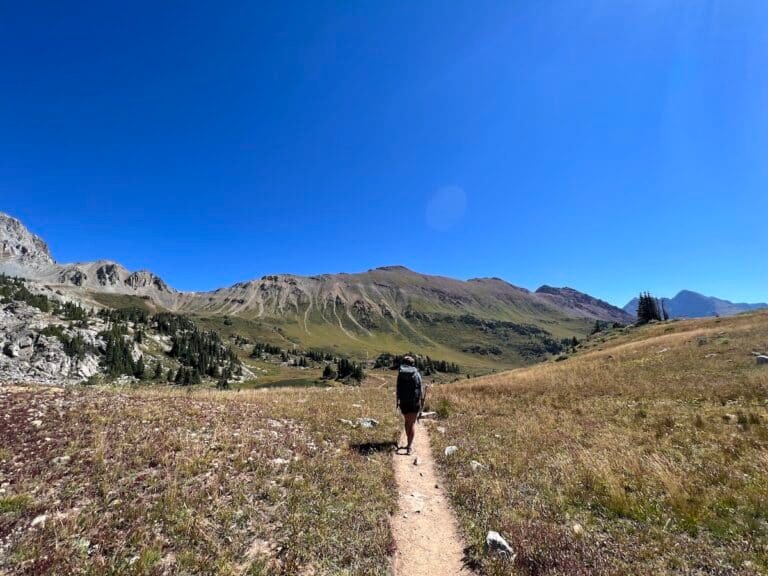 Hiker on the Four Pass Loop trail with mountains in the distance.