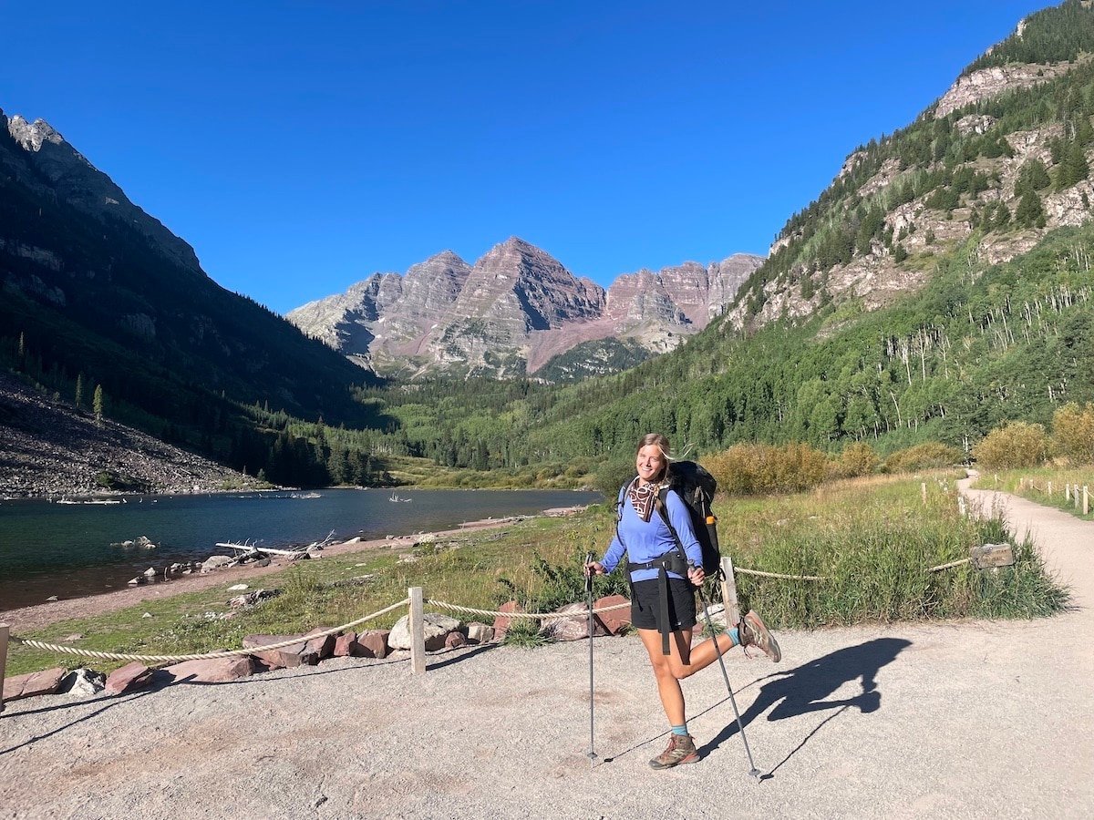 Hiker in front of Maroon Lake with the Maroon Bells in the background preparing to backpack the Four Pass Loop.