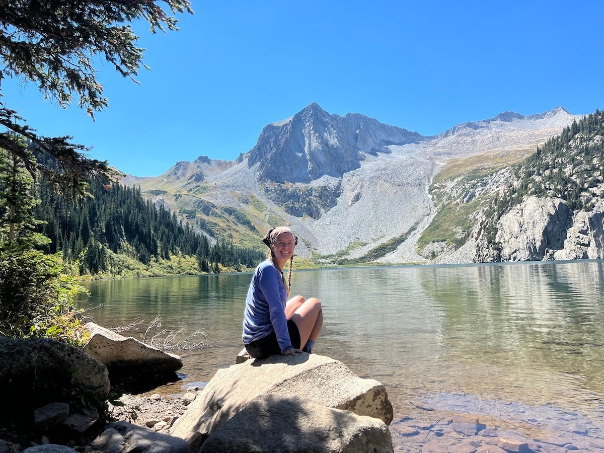 Hiker relaxing at Snowmass Lake on the Four Pass Loop.
