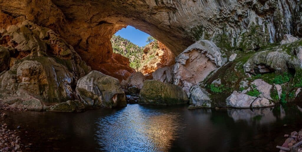 Natural bridge behind pool of water at Tonto Natural Bridge State Park in Arizona