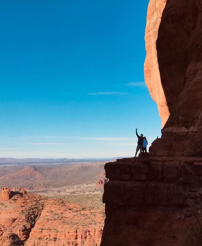 Silhouettes of two people standing at lookout on Cathedral Rock in Sedona