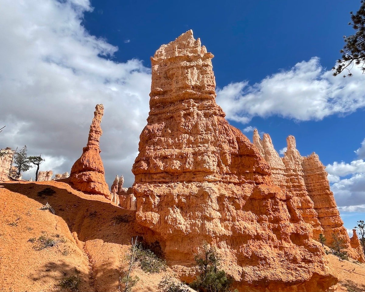 Queen Victoria hoodoo in the Queens Garden section of the Queens Garden Trail in Bryce Canyon National Park. There is a blue sky and clouds in the background.