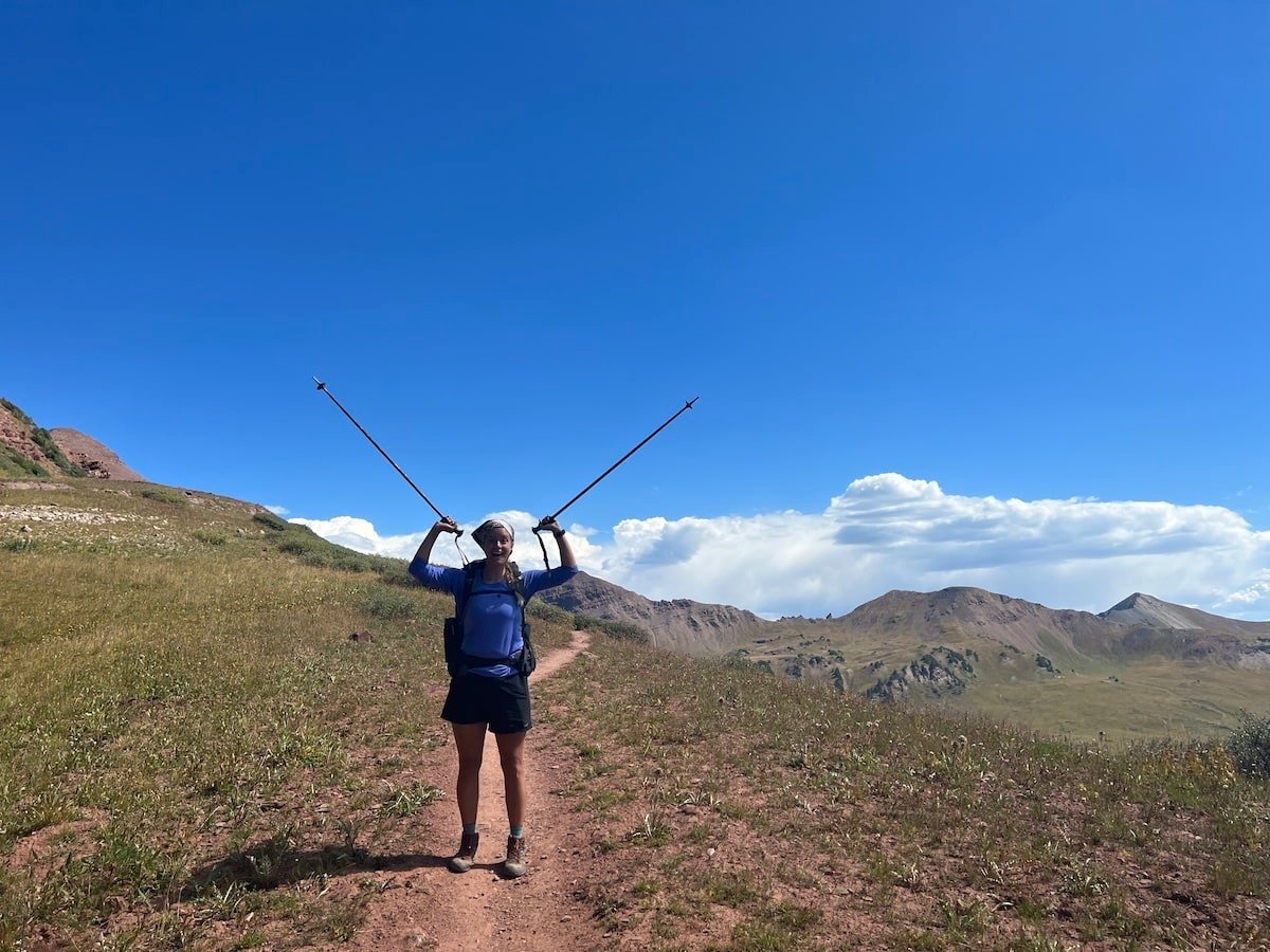Female hiker raising her trekking poles on the top of Frigid Air Pass on the Four Pass Loop