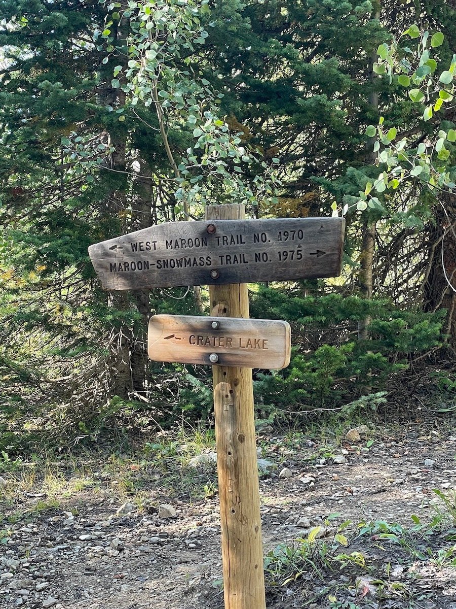 A wooden sign on the Four Pass Loop that marks the direction to Crater Lake