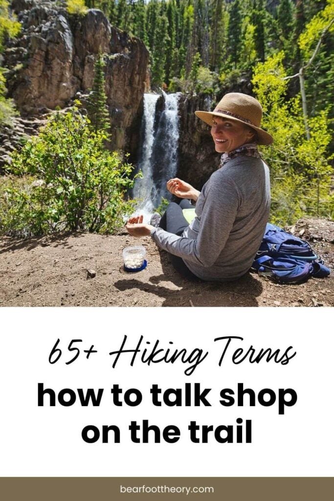 Pinnable image of woman sitting on rock overlooking waterfall eating a snack. Text reads "65+ hiking terms: How to talk shop on the trail"