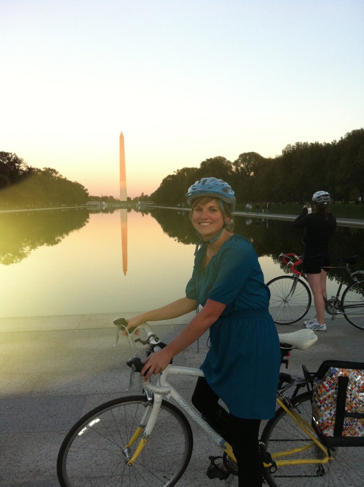 Alaina Hermiston on a bike in Washington DC in front of the Washington Monument at sunset
