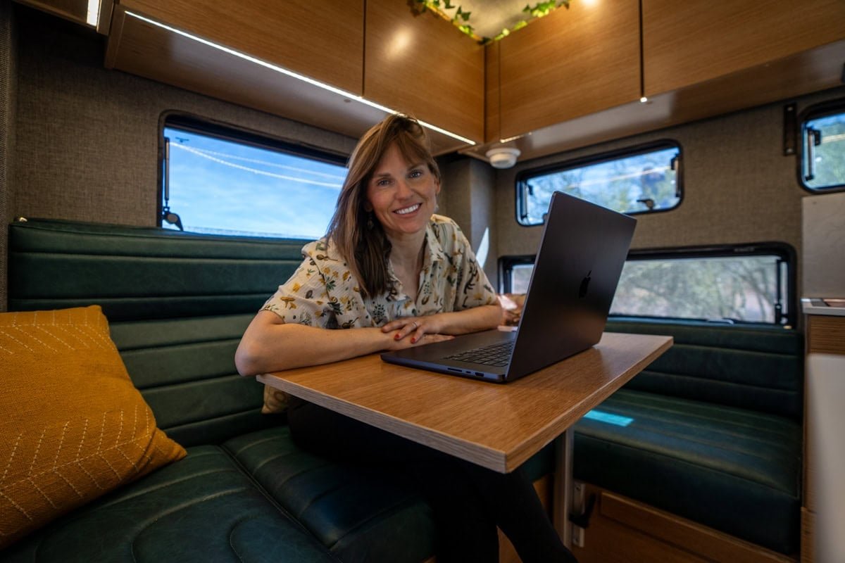 Alaina Hermiston working at the dinette inside the Rossmonster Baja Trail XL truck camper in the snow