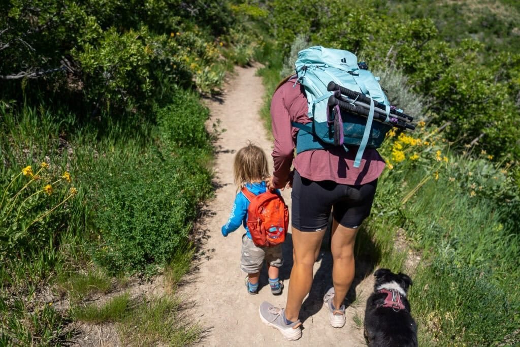 Alaina Hermiston and her toddler on a hiking trail. She is bending over to get something out of his backpack